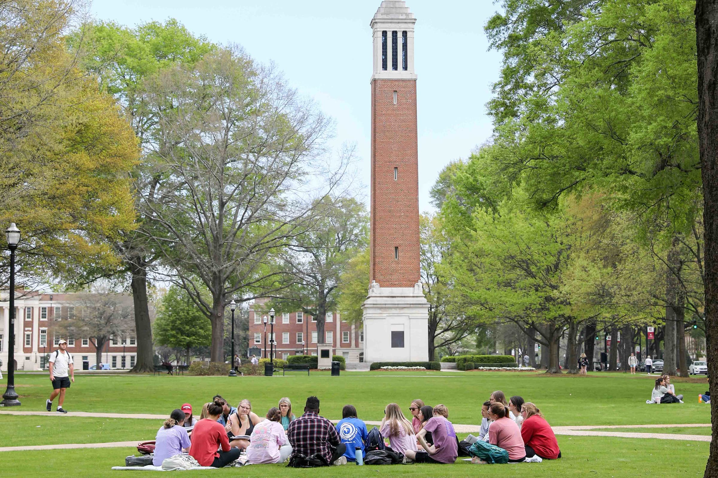 Students sitting in a circle in front of Denny Chimes
