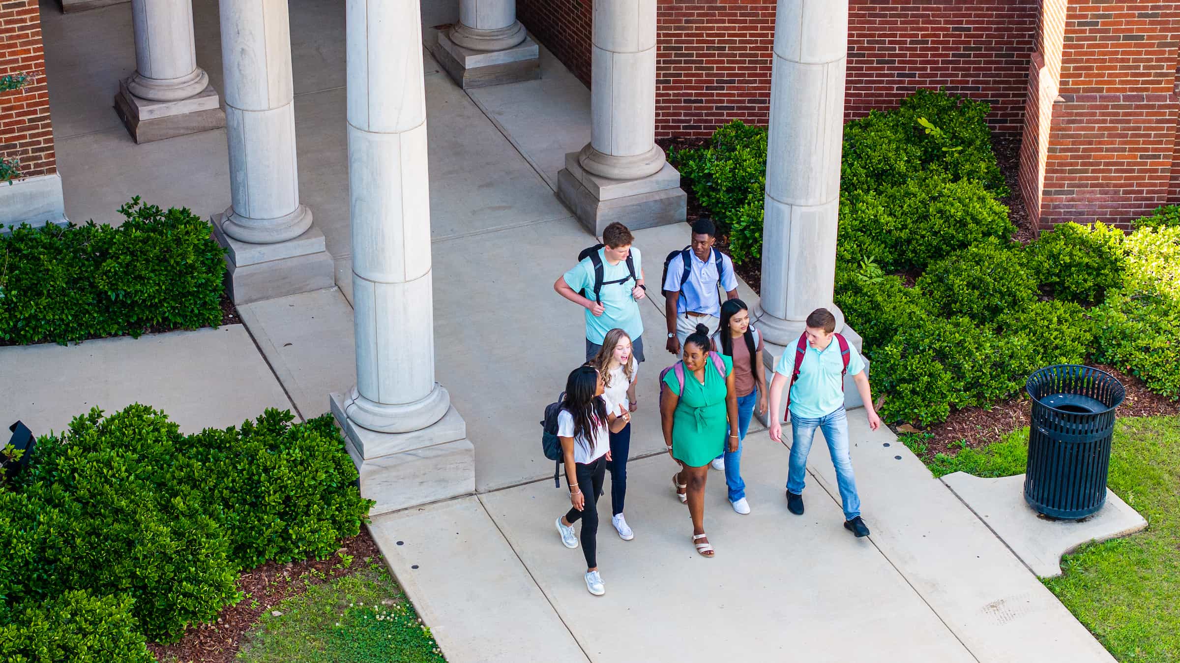 Aerial view of a group of students walking out of a building on campus